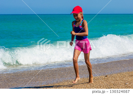 Young Girl Jogging on the Beach in a Baseball Cap Young Girl Jogging on the Beach in a Baseball Cap 130324087