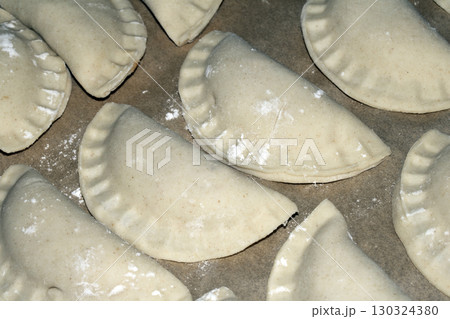 Close up of home made Chinese dim sum dumplings Jiaozi or Gyoza on bakking tray ready to be fried Close up of home made Chinese dim sum dumplings Jiaozi or Gyoza on bakking tray ready to be fried 130324380