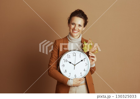 Cheerful Professional Woman with Clock and Autumn Leaves 130325033