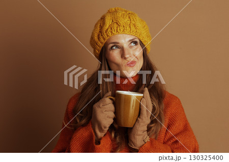 Thoughtful Woman with Warm Mug in Yellow Beret 130325400