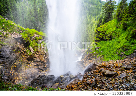 Johannes Waterfall cascades majestically amidst lush greenery in Obertauern, Austria. Visitors can enjoy the refreshing mist and serene beauty of this natural wonder year-round. 130325997