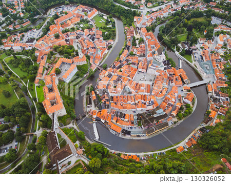 Discover the enchanting town of Cesky Krumlov from above, featuring its distinctive castle, winding Vltava River, and red-roofed buildings bathed in morning light. 130326052