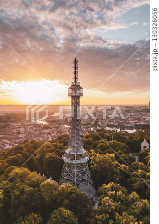 Petrin Lookout Tower stands majestically as the sun rises, casting a warm glow over the surrounding hills and vibrant tree canopy in Prague, revealing the city's beauty at dawn. Petrin Lookout Tower stands majestically as the sun rises, casting a warm glow over the surrounding hills and vibrant tree canopy in Prague, revealing the city's beauty at dawn. 130326056
