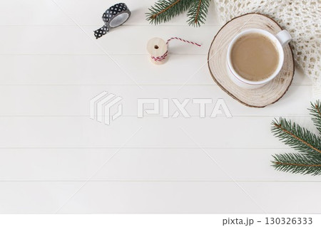 Christmas stationery still life. Cup of coffee, cut wooden round board. Green Christmas fir tree branches, wrapping tapes on white wooden table background. Winter festive flat lay, top view corner 130326333
