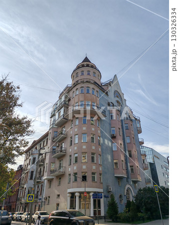 A towering beige residential building with repeating architectural elements, small balconies, and glass windows. This image showcases urban geometry and modern living in compact city spaces. 130326334