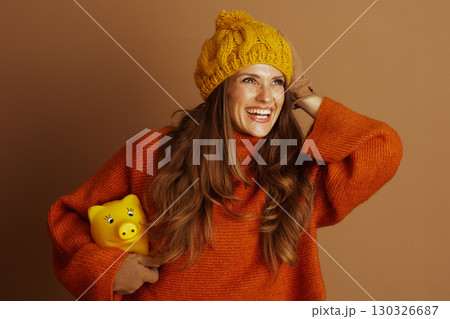 Playful Woman Saving Money with Piggy Bank Playful Woman Saving Money with Piggy Bank 130326687