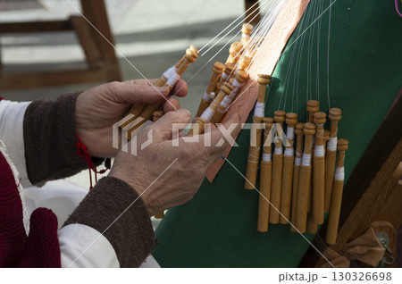 close-up of the hands of an elderly woman knitting with bobbin lace. close-up of the hands of an elderly woman knitting with bobbin lace. 130326698