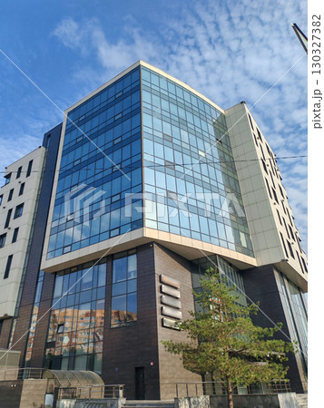 contemporary building with sharp angles, glass windows, and light paneling, reflecting modern architectural trends. The structure stands out as a symbol of urban growth and sleek design. 130327382