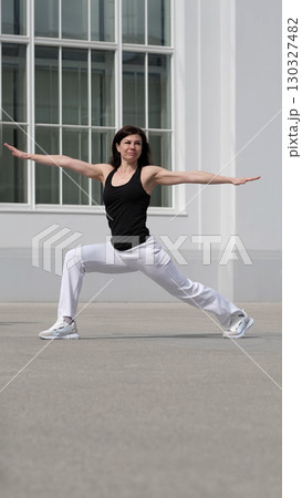 A woman performs a warrior yoga pose outdoors, exuding balance and strength. This image embodies mindfulness, wellness, and the pursuit of inner harmony. A woman performs a warrior yoga pose outdoors, exuding balance and strength. This image embodies mindfulness, wellness, and the pursuit of inner harmony. 130327482