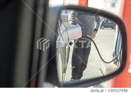 A man is filling up his car at a gas station A man is filling up his car at a gas station 130327496