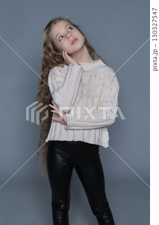 A girl with long wavy hair poses with a curious expression, resting her hand on her cheek. The introspective mood of the image represents deep thinking, future aspirations, and creative vision, making A girl with long wavy hair poses with a curious expression, resting her hand on her cheek. The introspective mood of the image represents deep thinking, future aspirations, and creative vision, making 130327547