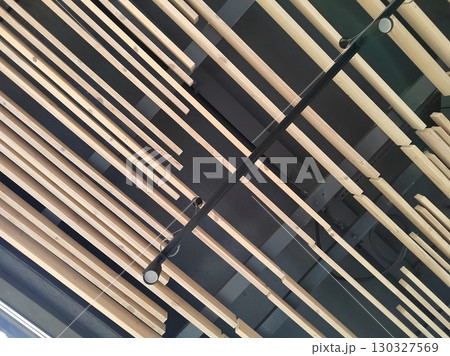 A detailed view of ceiling decor featuring natural wooden beams and industrial elements, highlighting modern architectural aesthetics. 130327569