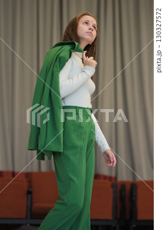 A stylish woman carrying her jacket over her shoulder, exuding elegance and confidence. The neutral background emphasizes her professional demeanor. 130327572