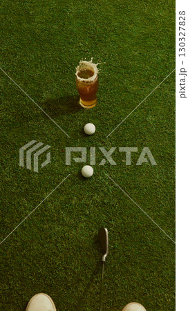 Beer glass splashing with golf club and balls on grass energetic dynamic scene Beer glass splashing with golf club and balls on grass energetic dynamic scene 130327828