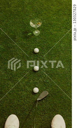 Golf player view of lined balls leading toward martini glass on grass with playful perspective Golf player view of lined balls leading toward martini glass on grass with playful perspective 130327829