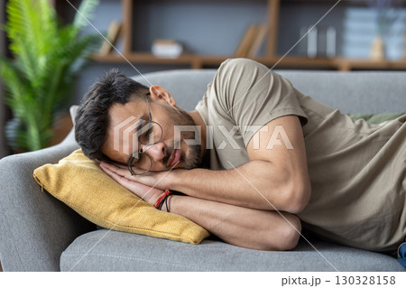 Close-up photo of a young Indian man sleeping and relaxing on the couch at home. 130328158