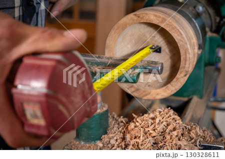 Close up of carpenter using measure tape on wooden bowl. 130328611