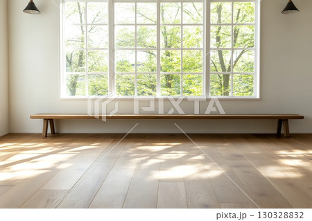 A long wooden bench sits beneath a large window overlooking a lush green landscape in a bright, minimalist room 130328832