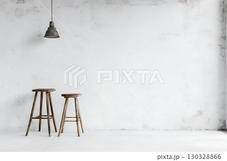 Two rustic wooden stools sit against a whitewashed wall under a hanging lamp 130328866