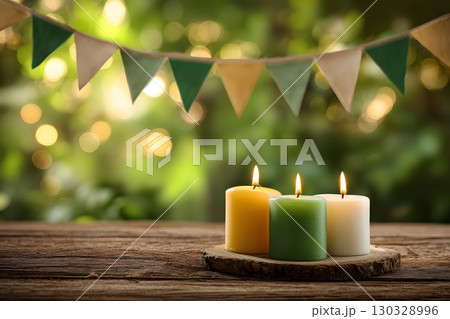 Three candles in saffron, white, and green colors on a wooden surface. Decorative triangular bunting in similar colors hangs in the background. Soft bokeh effect. India, Indian Independence Day. 130328996