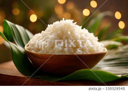A bowl of white rice served on a banana leaf, symbolizing the traditional Onam Sadya feast in Kerala, India. The background features soft bokeh lights. 130329548
