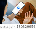 アジア人女性がスマートフォンのAIアシスタントに話しかける様子・音声認識・テクノロジーのある暮らし 130329954
