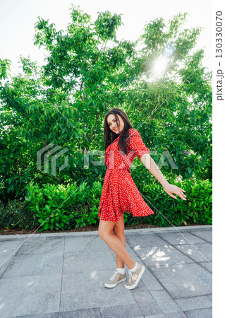 women in a red polka dot dress smiling on the street women in a red polka dot dress smiling on the street 130330070