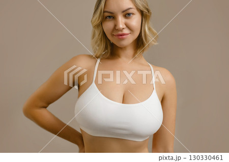 Young attractive woman with big breasts in white lingerie, showing natural beauty, bust aesthetics, skincare, plastic surgery concept, sensuality and confident body care. 130330461