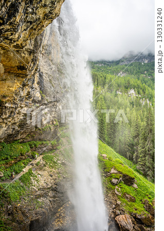 Johannes Waterfall cascades powerfully near Obertauern, Austria. Surrounded by lush green forests, the waterfall creates a breathtaking view amid the stunning Alpine landscape. 130331240
