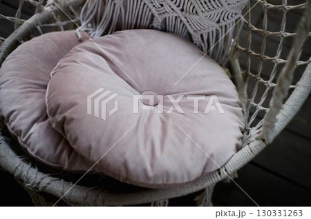 The swing is light wicker with a soft pillow in the style of macrome. Boho style, garden design. 130331263
