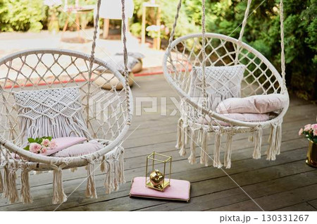 The swing is light wicker with a soft pillow in the style of macrome. Boho style, garden design. 130331267