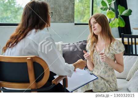 Young woman at therapy session with female psychologist, social worker 130332015