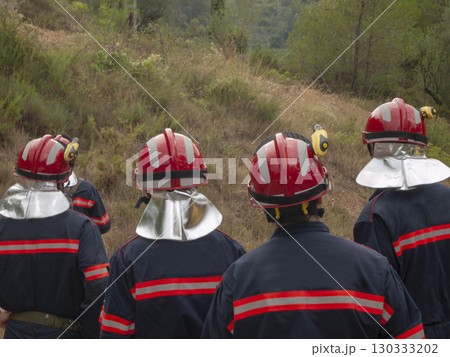 group of four firefighters observing the smoking mountain group of four firefighters observing the smoking mountain 130333202