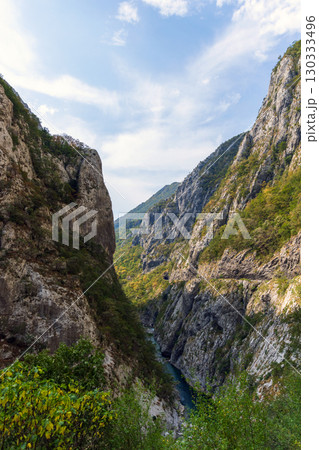 Vertical photo of a canyon with a calm, emerald green river 130333496