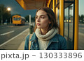 Young woman is standing at the city bus stop 130333896