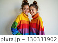 Two women in bright rainbow striped sweaters smile at the camera. The concept of happiness and 130333902