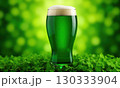 Glass of green foamy irish beer stands on green grassy clover background. St. Patrick Day 130333904