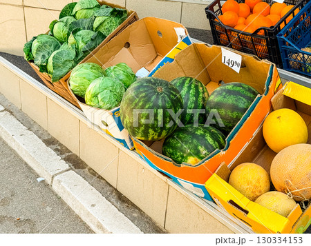 Fresh fruits and vegetables including watermelon, cabbage, melon and orange displayed in cardboard boxes. Market trade, agriculture produce and healthy food supply for commerce and seasonal nutrition. 130334153