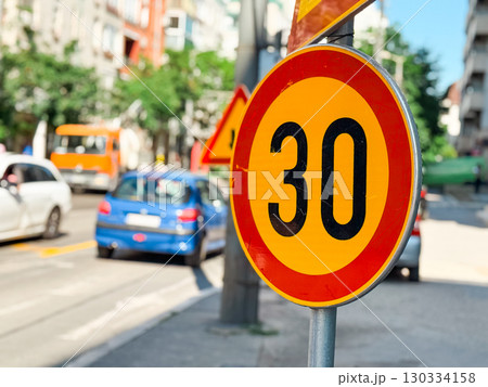 Speed limit sign showing maximum 30 kilometers per hour on a public road. Regulation, prevention and urban traffic safety for vehicles, transportation order and controlled city environment Speed limit sign showing maximum 30 kilometers per hour on a public road. Regulation, prevention and urban traffic safety for vehicles, transportation order and controlled city environment 130334158