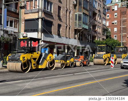 Row of road rollers on a city street. Heavy construction equipment, infrastructure, and maintenance work in urban settings. Row of road rollers on a city street. Heavy construction equipment, infrastructure, and maintenance work in urban settings. 130334184