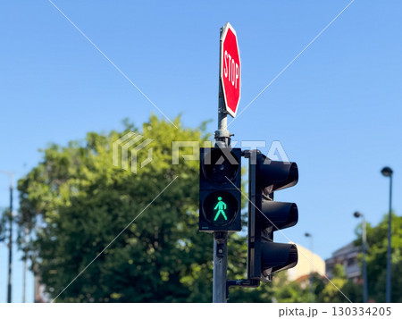 Green pedestrian traffic light. Urban crosswalk, mobility, and transportation safety in a cityscape. 130334205