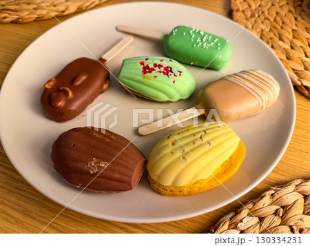 Assorted desserts on a plate, colorful cakes and popsicles. Modern food styling. Concept of variety, sweets, aesthetics of food. 130334231