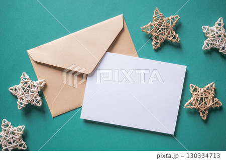White blank greeting or invitation card and envelope with Christmas decoration on green background. 130334713