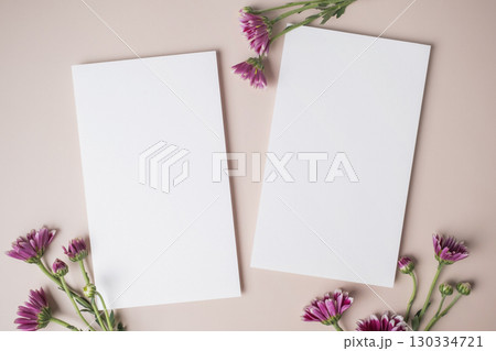 White blank greeting or invitation card with purple flower decoration on beige background. 130334721