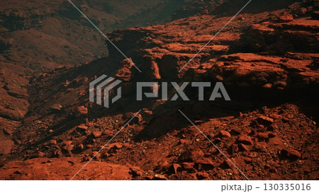 Witness the mesmerizing grandeur of crimson stone canyons harmoniously intertwined with towering mountains, overlooking a serene and magnificent valley. 130335016