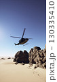 An old American military retro helicopter hovers above a rocky desert landscape, showcasing its capabilities in this rugged terrain. 130335410