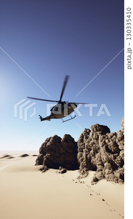An old American military retro helicopter hovers above a rocky desert landscape, showcasing its capabilities in this rugged terrain. 130335410