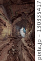 A cave with an abundance of rocks and water, illuminated by rays of light penetrating through the stone walls. 130335417