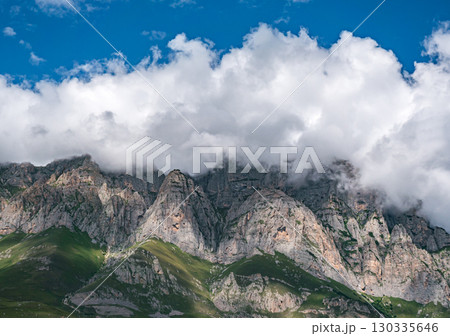 Stunning mountain landscape under vibrant blue sky with swirling clouds in the background Stunning mountain landscape under vibrant blue sky with swirling clouds in the background 130335646