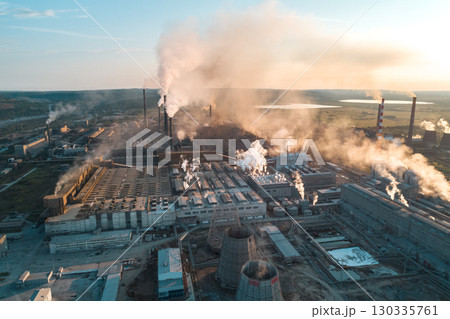 Air pollution from industrial facilities causes environmental concerns in urban areas during sunset hours. 130335761
